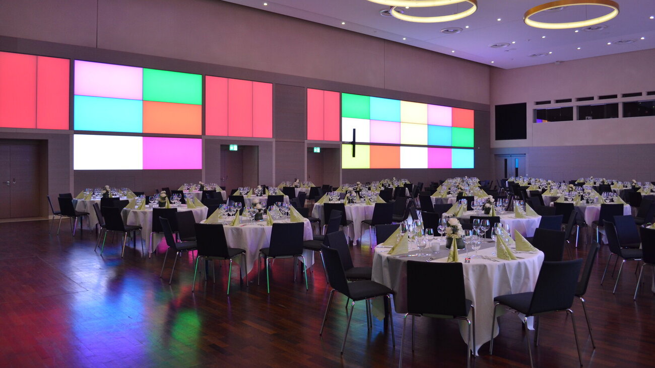 Festlich gedeckter Goldsaal mit Galabestuhlung und bunter Wandbeleuchtung.
