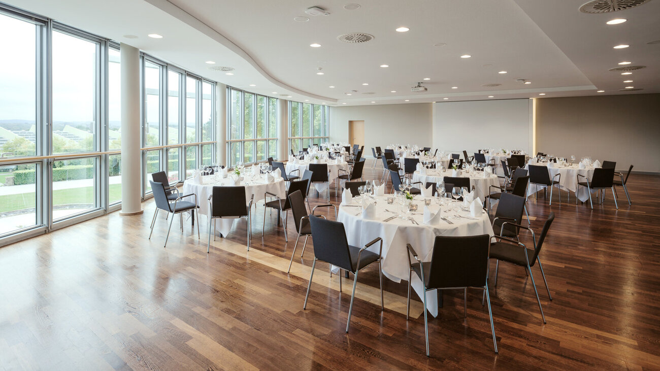Festlich gedeckter Saal 8 mit runden Tischen und Blick auf den Rosengarten.